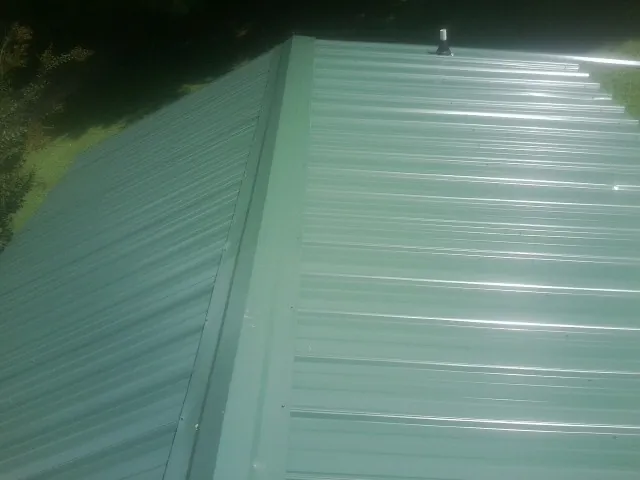 New green metal panels meeting at the ridge of a roof — Flat Roof Repair work by our crew in San Rafael