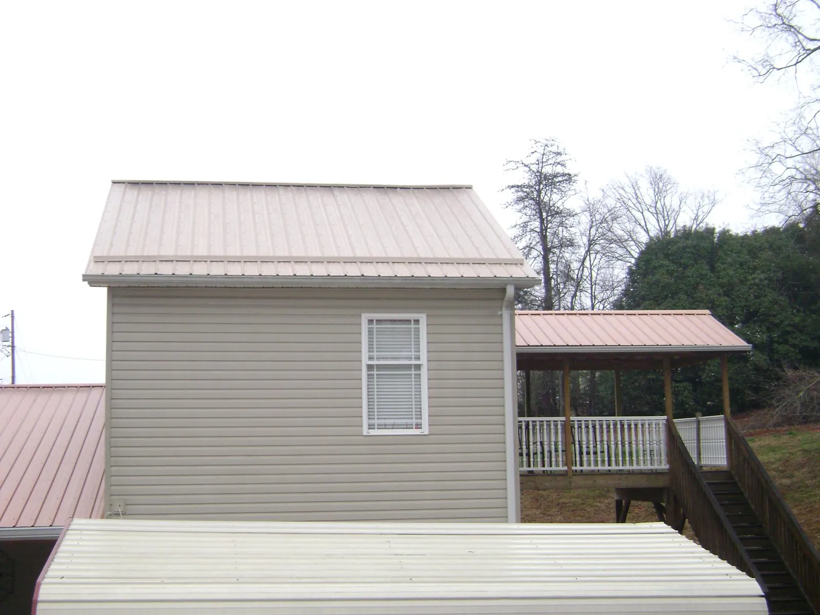 Tan metal roofs on a two story addition and attached porch, from a Roof Replacement job in San Rafael