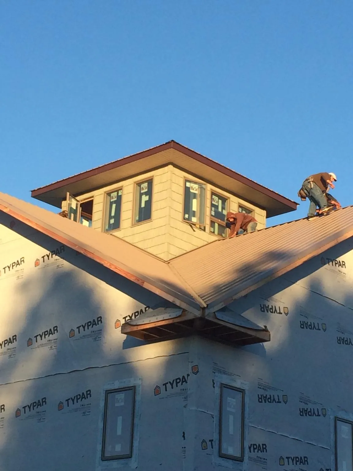 Roofers working around a rooftop cupola on a new metal roof at sunset — Roof Waterproofing in San Rafael by Roofing Brothers
